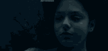 a woman is swimming underwater with her eyes closed in a dark room .