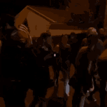 a group of people are standing on the side of the road at night .