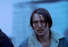 a man with long hair wearing a denim jacket