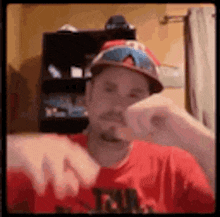a man wearing a red shirt and a hat is making a face .