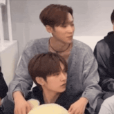 two men are sitting next to each other and one of them is holding another man 's arm