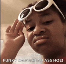 a girl wearing sunglasses is making a funny face and says funky dawg head ass hoe .