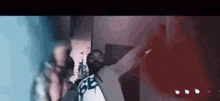 a group of people are standing next to each other in a room . one of the people is wearing a mask .