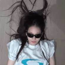 a woman wearing sunglasses and a white shirt with the letter g on the front