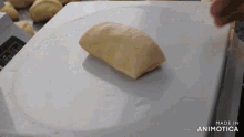 a piece of dough is on a cutting board that says made in animotica on it