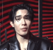 a young man wearing a black leather jacket is smiling and making a funny face .
