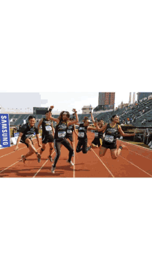 a group of people are standing on a track with a samsung sign in the background
