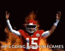 a football player with the number 15 on his jersey is standing in front of flames .
