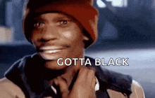 a man wearing a red beanie is smiling and the words gotta black are above him .
