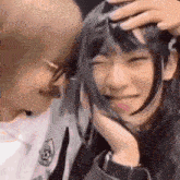 a man is petting a woman 's head while she is smiling and laughing .