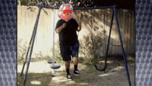 a man is standing on a swing set with a balloon on his face