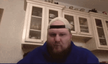 a man with a beard wearing a hat and a blue jacket