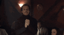 a man in a suit and tie is clapping his hands in a crowd