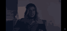 a woman in a black dress is sitting on a couch in a dark room .