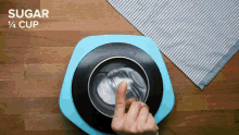 a person 's finger is pointing at a bowl of sugar