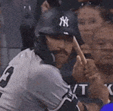 a man wearing a ny hat is swinging his bat