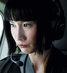 a close up of a woman wearing bose headphones and a microphone