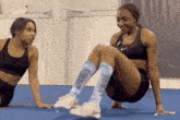 two women are doing exercises together on a blue mat .