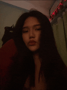 a woman with long dark hair is taking a selfie in a dark room .