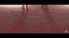 two people are dancing on a red floor with their shadows on the floor .