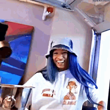 a woman with blue hair is wearing a bucket hat and a sweatshirt with a monkey on it