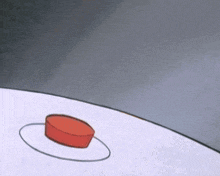 a red button with a circle around it is on a white surface .