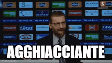 a man in a suit and tie is standing in front of a screen that says aggiacciante