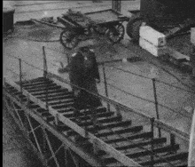 a black and white photo of a man walking on a bridge