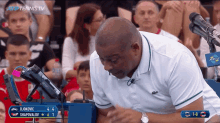a man in a white shirt is watching a tennis match