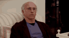 a bald man wearing glasses is sitting on a striped couch