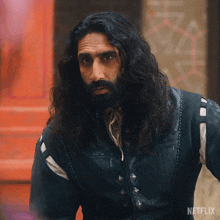 a man with long hair and a beard is wearing a jacket that says netflix on it