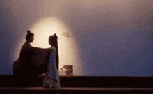 a man and woman are standing next to each other in front of a wall .