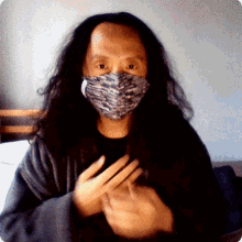 a man wearing a face mask is making a hand gesture