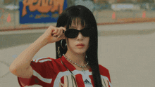 a woman wearing sunglasses and a green bandana has a necklace that says i love you