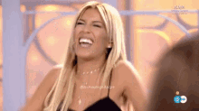 a woman in a black dress is laughing on a television show