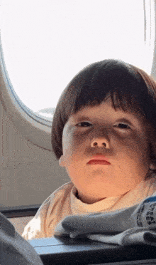 a little boy is looking out of an airplane window .