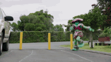 a person in a green and pink costume is walking down a street