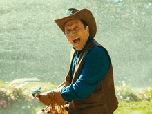 a man wearing a cowboy hat and vest is standing in the rain