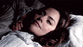 a woman in a white dress is laying in a bed