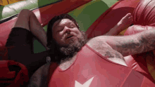 a man in a red tank top with a white star on it is laying down