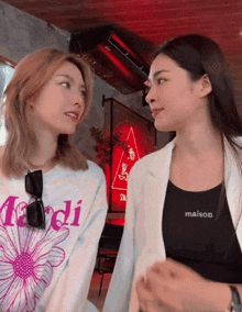 two women are looking at each other and one has a shirt that says maison on it