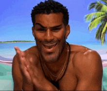 a shirtless man is smiling and clapping in front of a beach