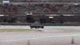 a black car is driving on a track with a green line