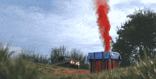 a box with red smoke coming out of it in a field