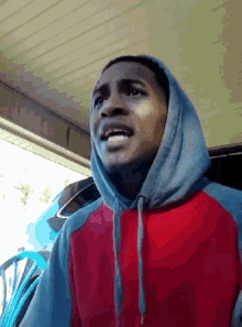 a man in a red and blue hoodie is making a face