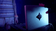 a person is holding a laptop with a diamond sticker on it