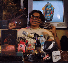 a man is holding a pair of wolverine claws in front of a television screen that says eckoteca