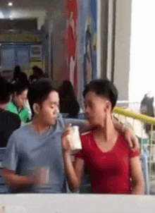 a man and a woman are sitting at a table in a restaurant drinking milkshakes .