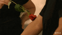 a person is holding a red rose in their arm with netflix written on the bottom right