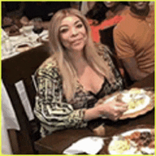 a woman is sitting at a table eating a plate of food .